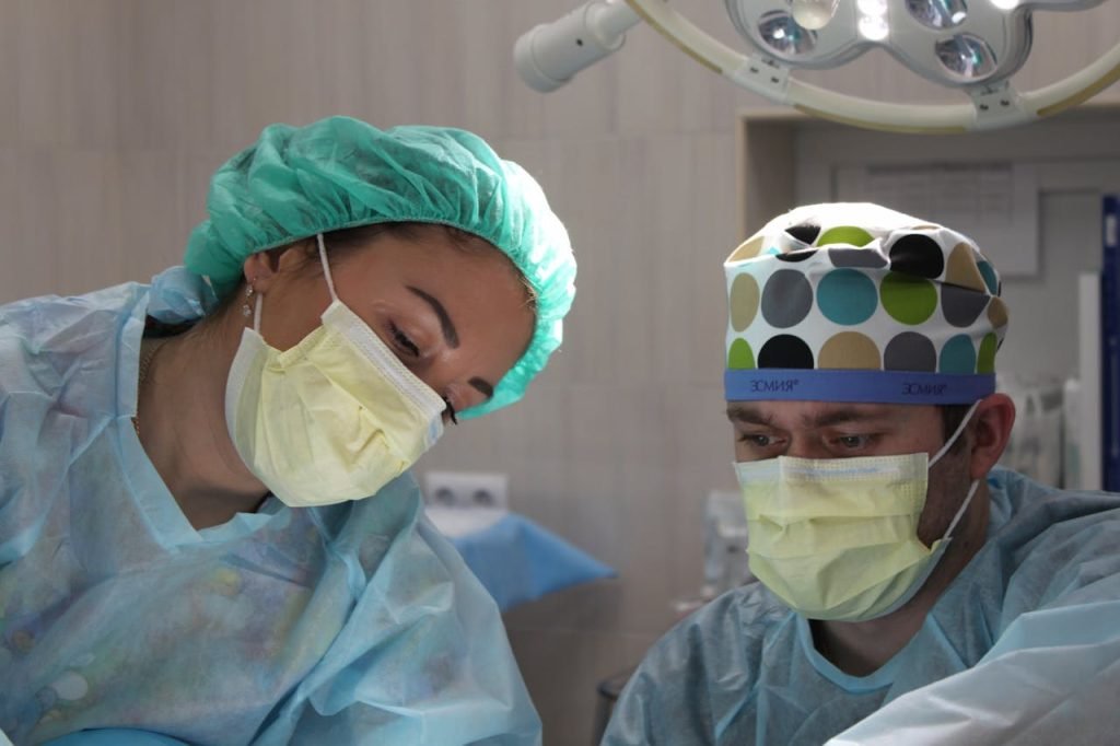 Surgeons wearing masks and scrubs conduct an operation in a hospital setting.